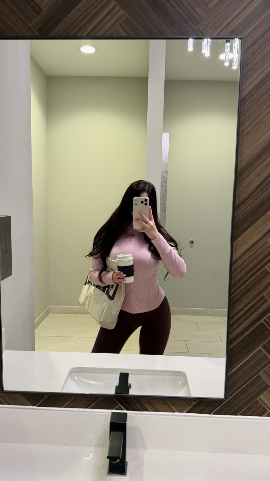 Asya taking a mirror selfie with a coffee